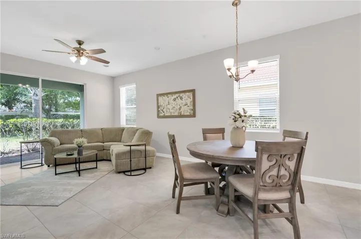 Dining area featuring baseboards, a healthy amount of sunlight, and ceiling fan with notable chandelier