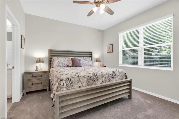Carpeted bedroom featuring baseboards, ceiling fan, and ensuite bathroom