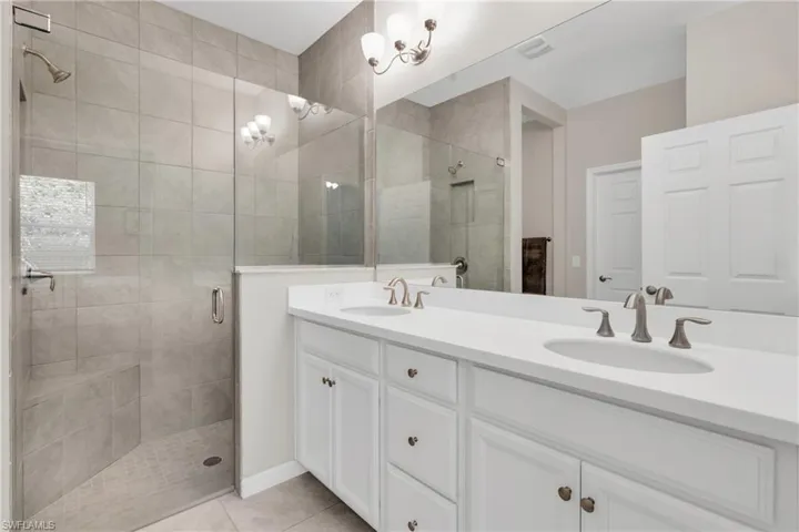Full bathroom featuring a shower stall, double vanity, tile patterned flooring, and a sink