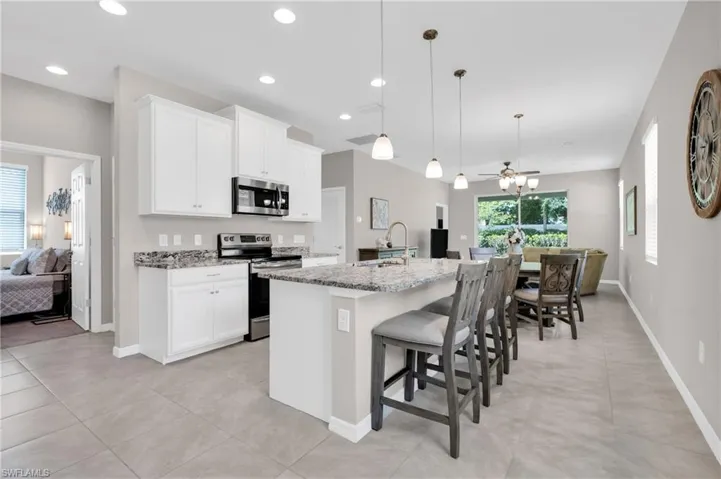Kitchen with a breakfast bar area, a sink, stainless steel appliances, and light stone counters