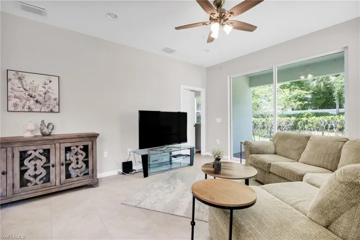 Living room featuring light tile patterned floors, baseboards, ceiling fan, and visible vents