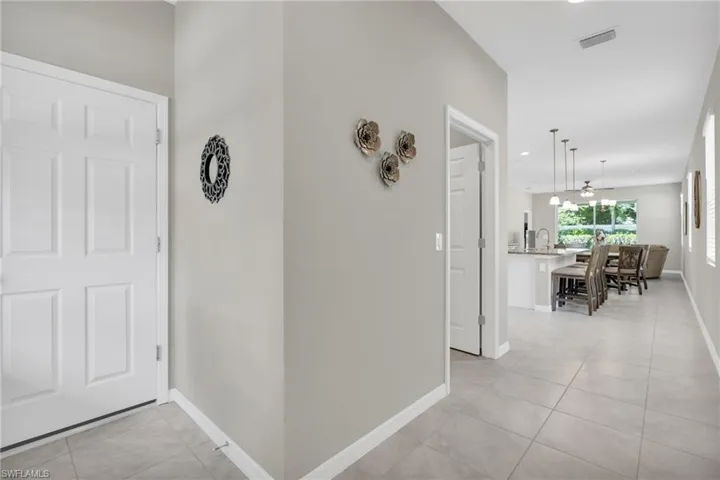 Corridor with baseboards, visible vents, a chandelier, and light tile patterned floors