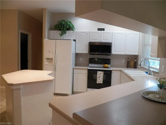 Kitchen with sink, a center island, edge of breakfast bar