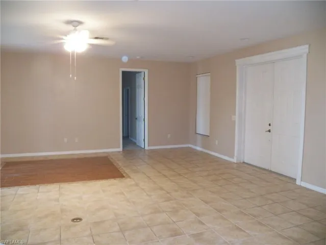 Living room featuring ceiling fan and light tile patterned floors & front doors