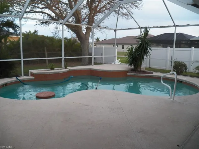 View of swimming pool with table by the bench and jets