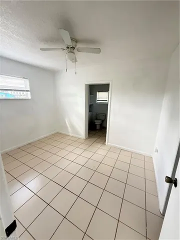 Empty room featuring light tile patterned floors, a ceiling fan, and a textured ceiling