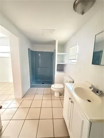 Full bathroom with vanity, light tile patterned floors, and a stall shower
