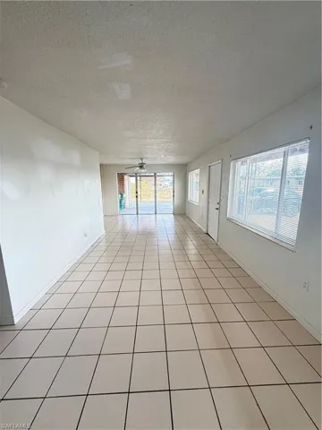 Spare room with a textured ceiling, ceiling fan, and light tile patterned floors