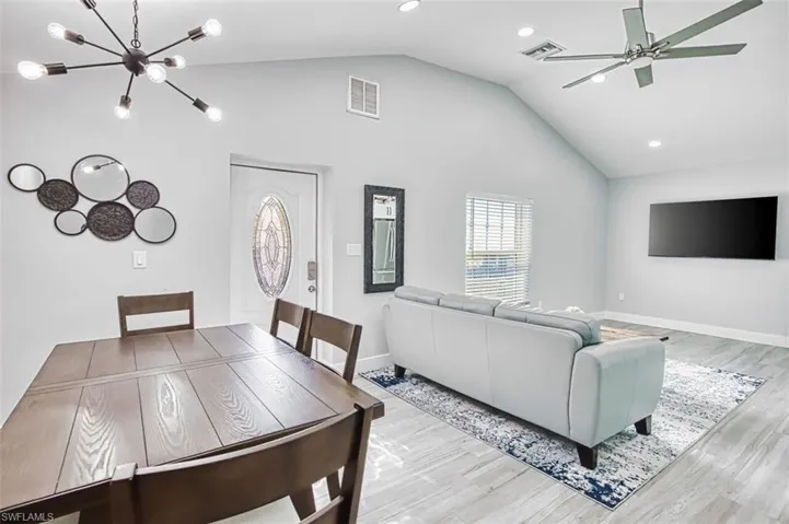 Living room featuring light wood-type flooring, suspended lighting, and ceiling fan