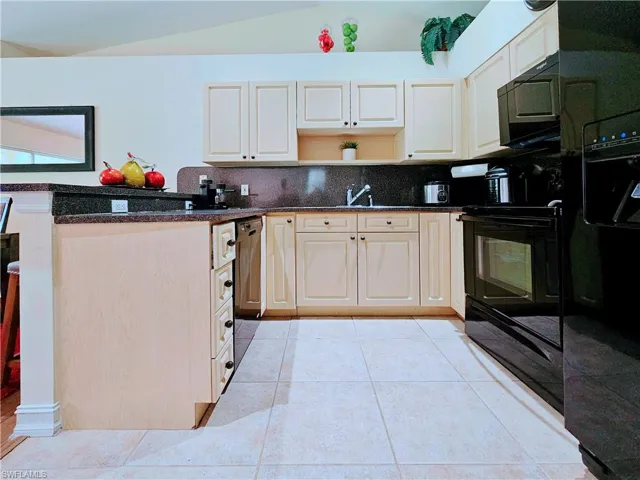 Kitchen with black appliances, lofted ceiling, open shelves, backsplash, and light tile patterned floors