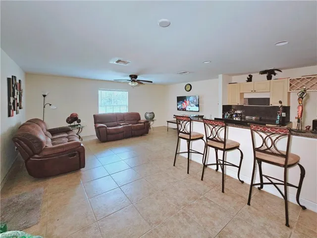 Kitchen with a kitchen bar, dark countertops, open floor plan, backsplash, and light tile patterned floors