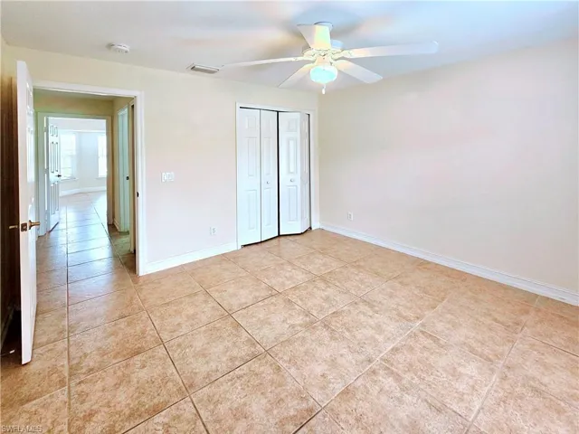 Unfurnished bedroom featuring light tile patterned floors, a closet, and ceiling fan