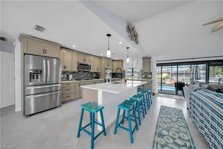 Kitchen with backsplash, stainless steel appliances, a breakfast bar area, a kitchen island with sink, and recessed lighting