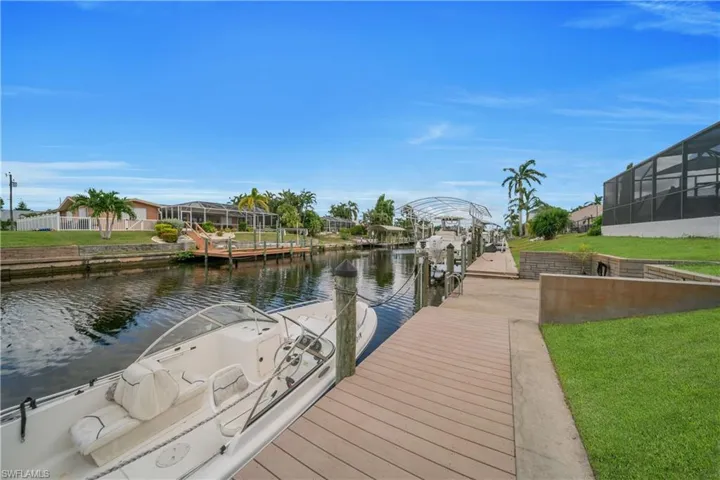 Dock area featuring a water view, a sunroom, a yard, boat lift, and a lanai