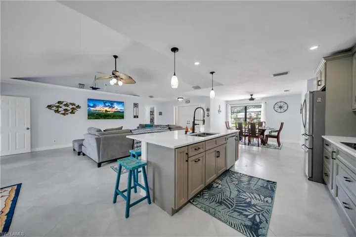Kitchen featuring open floor plan, a kitchen breakfast bar, ceiling fan, vaulted ceiling, and pendant lighting
