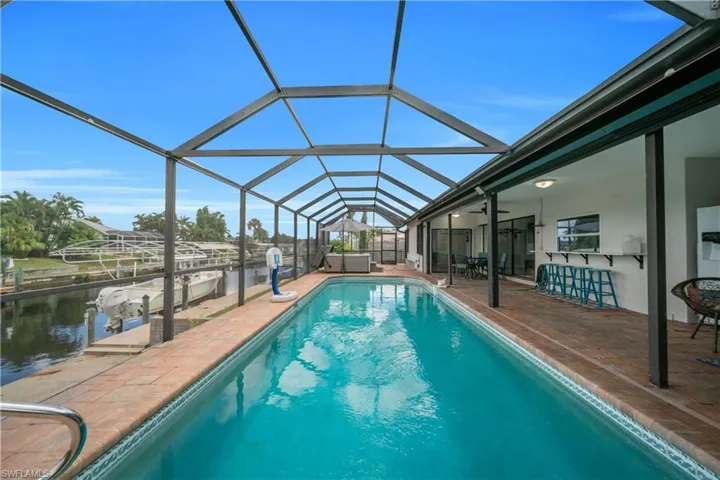 Swimming pool featuring a sunroom, a lanai, a water view, and a dock