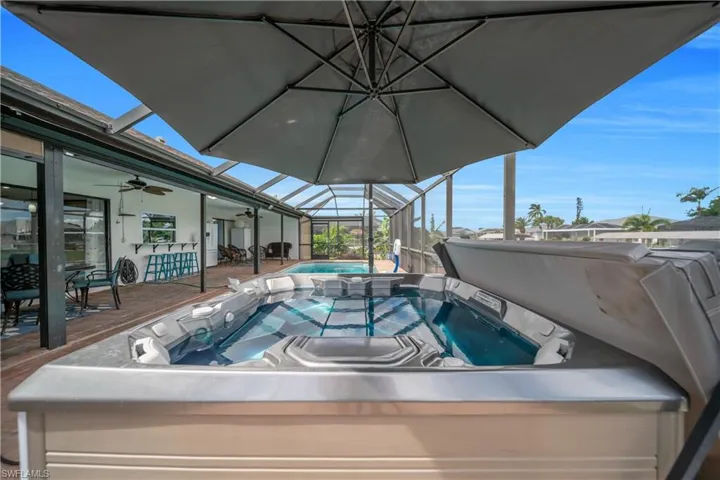 View of pool featuring a hot tub, a sunroom, a lanai, ceiling fan, and a patio