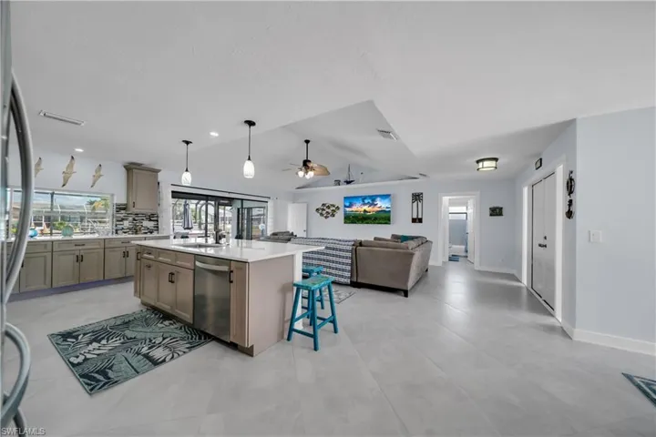 Kitchen with a center island with sink, light stone counters, decorative light fixtures, a kitchen bar, and open floor plan