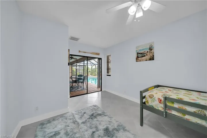 Bedroom featuring a sunroom, access to exterior, light tile patterned flooring, and ceiling fan