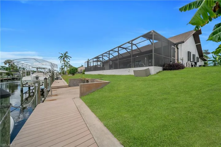 Dock area featuring a sunroom, a yard, a lanai, boat lift, and a water view
