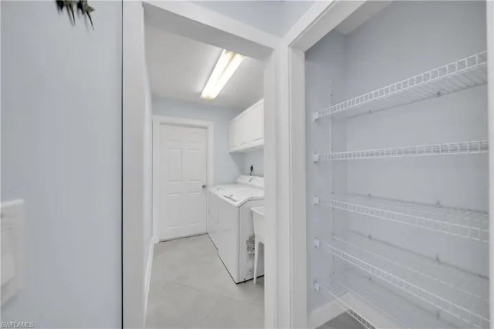 Washroom with cabinet space, light tile patterned flooring, and washing machine and clothes dryer