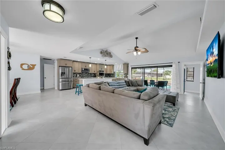 Living area with vaulted ceiling, ceiling fan, and light tile patterned floors