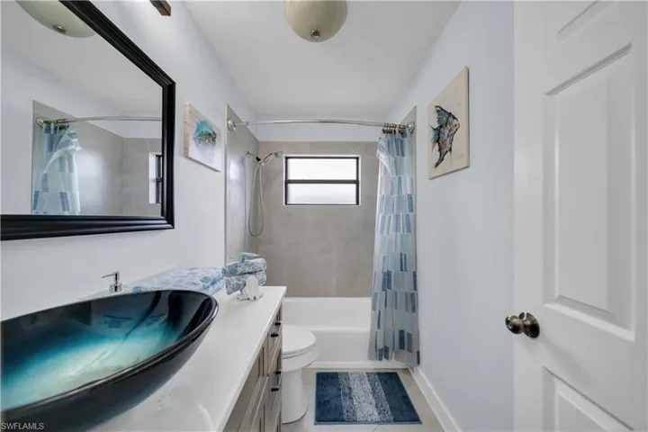 Bathroom featuring shower / bath combination with curtain, vanity, and light tile patterned flooring