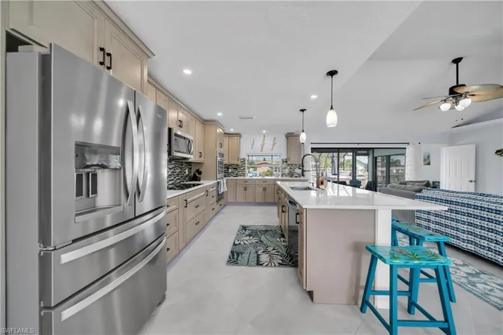Kitchen with stainless steel appliances, open floor plan, tasteful backsplash, light stone counters, and recessed lighting