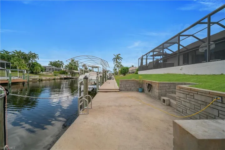 Dock area featuring a water view, a sunroom, boat lift, a lanai, and a patio area