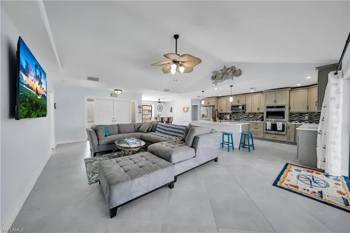 Living room featuring ceiling fan, lofted ceiling, and light tile patterned flooring