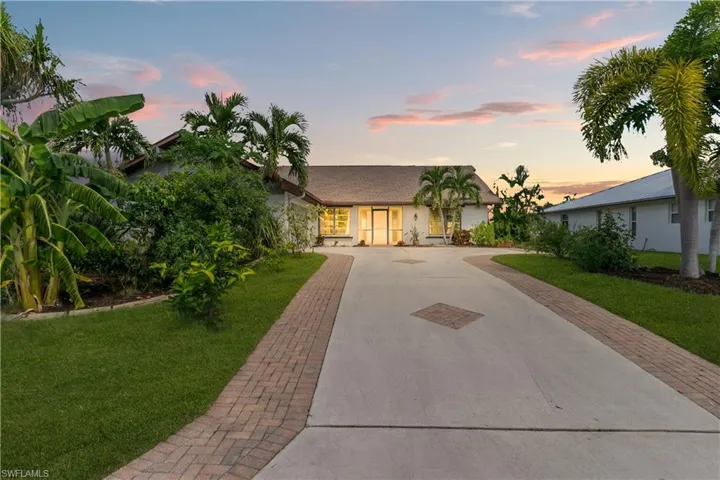 View of front of property featuring decorative driveway and a front yard