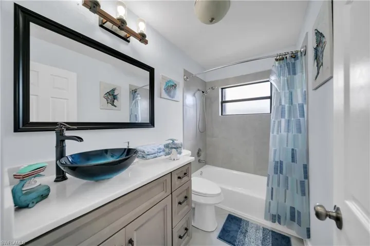 Bathroom featuring shower / tub combo with curtain, vanity, and light tile patterned floors