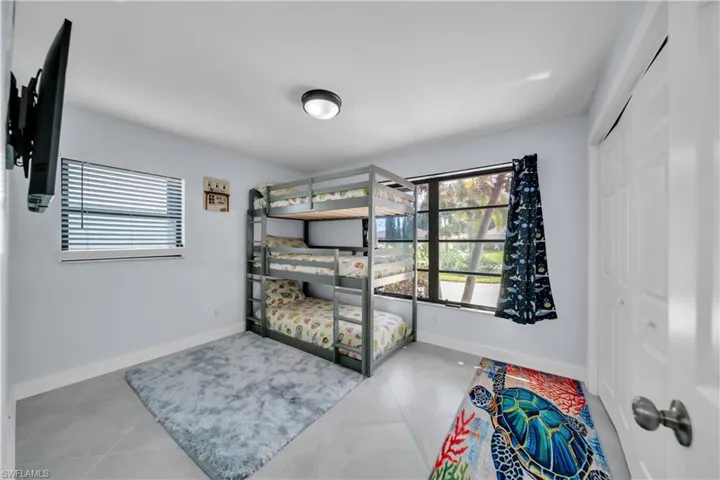 Bedroom with multiple windows, light tile patterned floors, and a closet