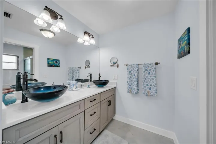 Full bath featuring double vanity, light tile patterned flooring, and a stall shower