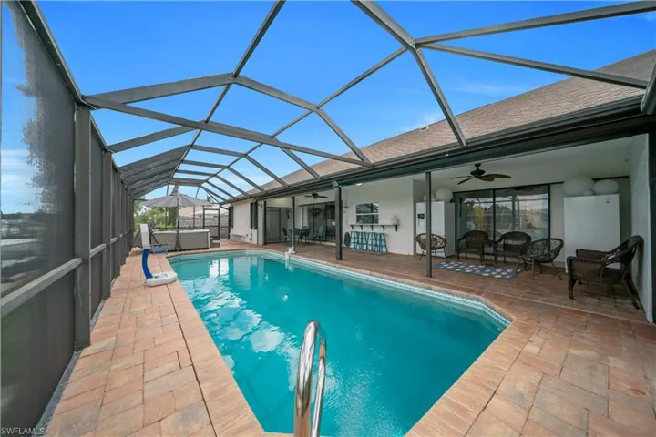 Outdoor pool with ceiling fan, a l sunroom, glass enclosure, a patio, and an outdoor hangout area