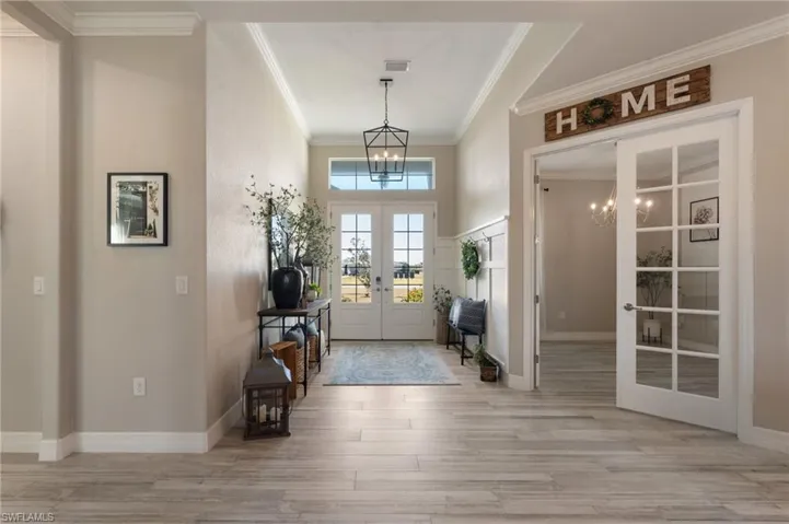 Entryway featuring french doors, ornamental molding, light hardwood / wood-style flooring, and a notable chandelier