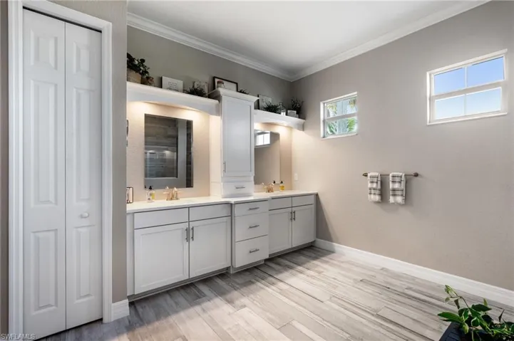 Primary bathroom with hardwood / wood-style flooring, vanity, and ornamental molding