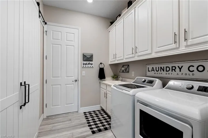 Laundry room with sink, cabinets, washer, dryer, a barn door,