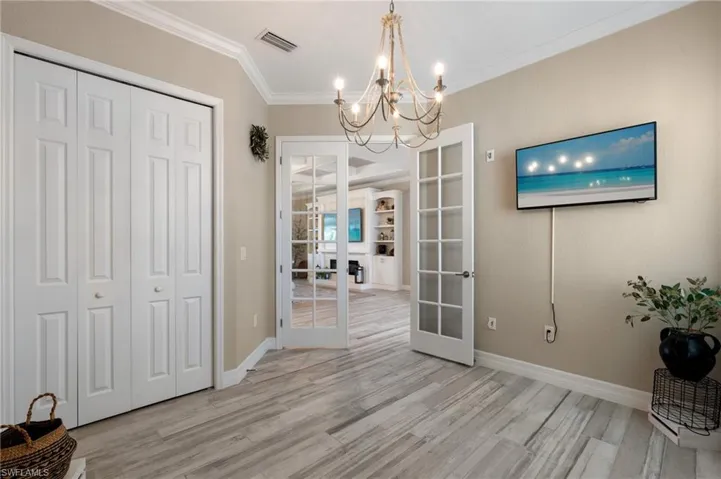 Den with french doors, ornamental molding, and an inviting chandelier