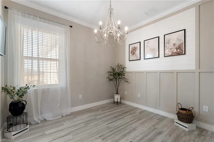 Den featuring a chandelier, ornamental molding, land a healthy amount of sunlight
