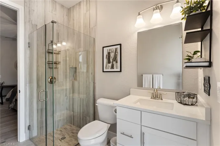 Bathroom with vanity, toilet, and a shower with shower door
