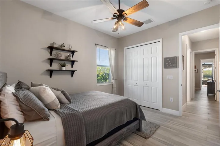 Bedroom featuring ceiling fan, a closet, multiple windows, and light hardwood / wood-style flooring