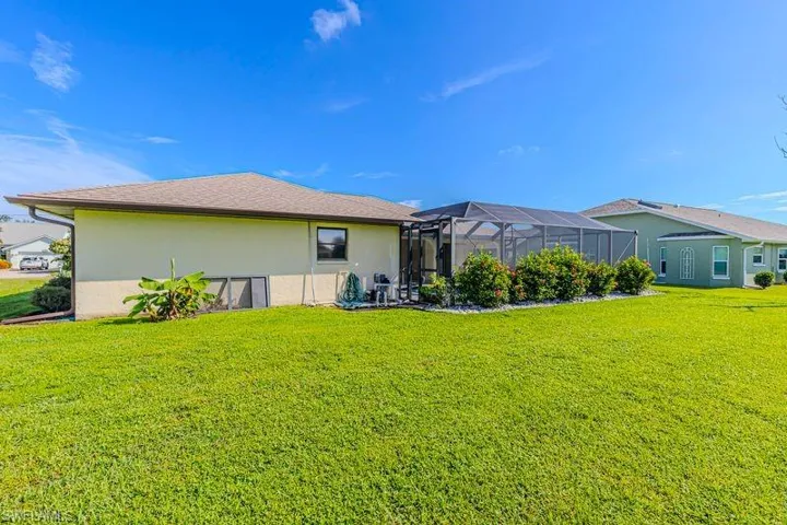 Back of house with a sunroom, stucco siding, a lawn, and a lanai
