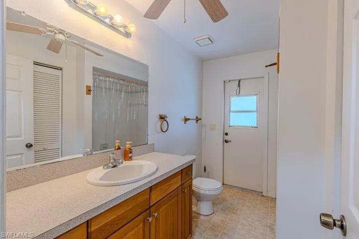 Bathroom with vanity, a shower with shower curtain, and a ceiling fan