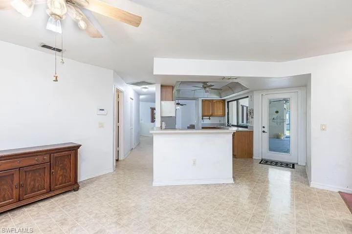 Kitchen with a ceiling fan, brown cabinets, light countertops, and a peninsula