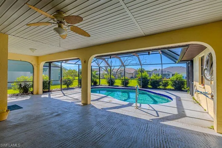 Swimming pool featuring a sunroom, a patio, glass enclosure, and a ceiling fan