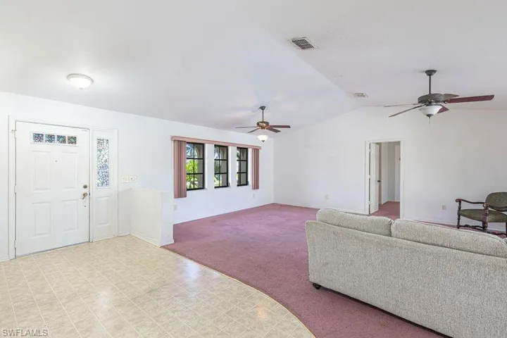 Living room with carpet, lofted ceiling, and a ceiling fan