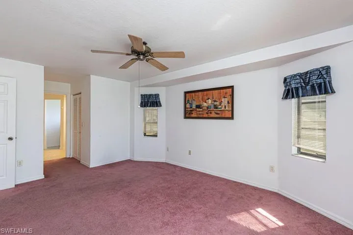 Carpeted spare room with baseboards and ceiling fan