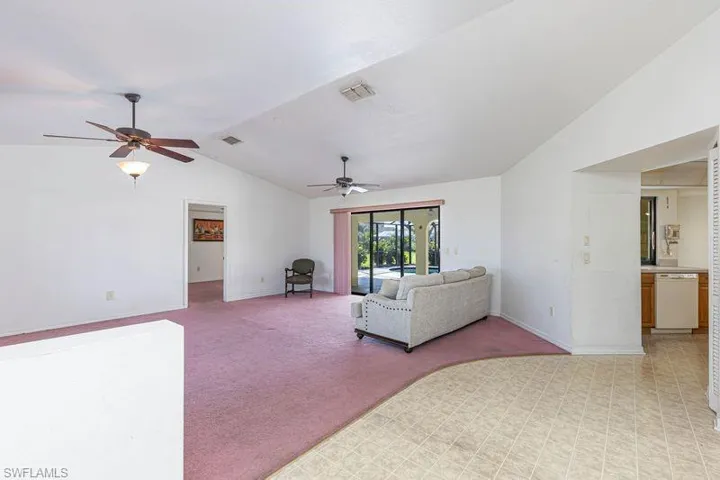 Living area with light carpet, lofted ceiling, and ceiling fan
