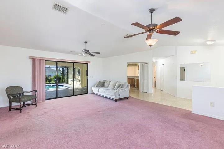 Living room with carpet floors, vaulted ceiling, and a ceiling fan
